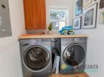 The washer and dryer area is stocked with laundry soap, beach towels, a drying rack, dog toys, and a stool.